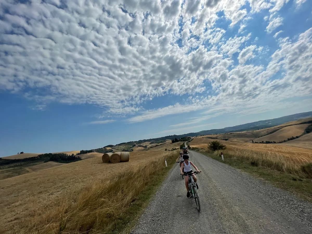Riders on e-bikes setting off along a white gravel road through the rolling Tuscan hills near Peccioli