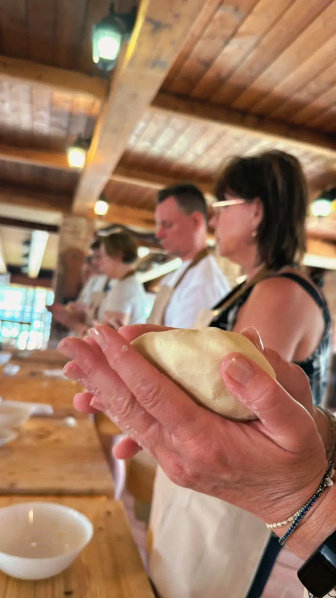 Hands shaping pizza dough during the hands-on class in the farmhouse
