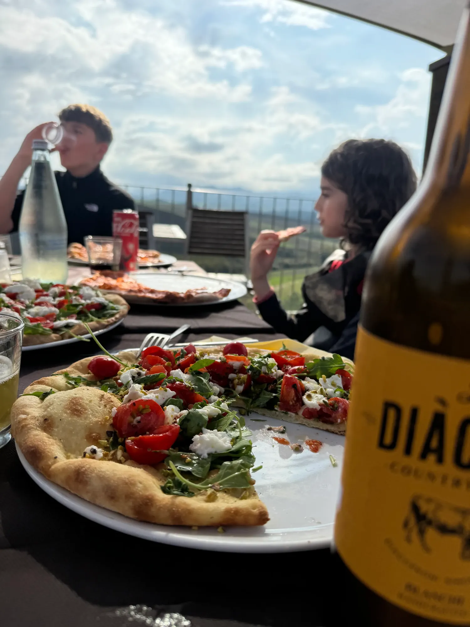 Freshly baked pizzas with cherry tomatoes and arugula on the lunch table, Tuscan view behind