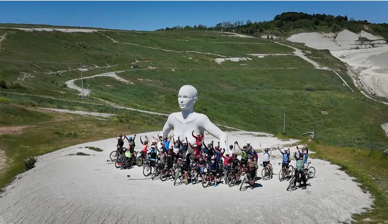 A group of e-bike riders in front of one of the Giants of Peccioli