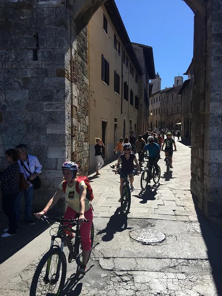 E-bikers riding through a medieval stone street of San Gimignano