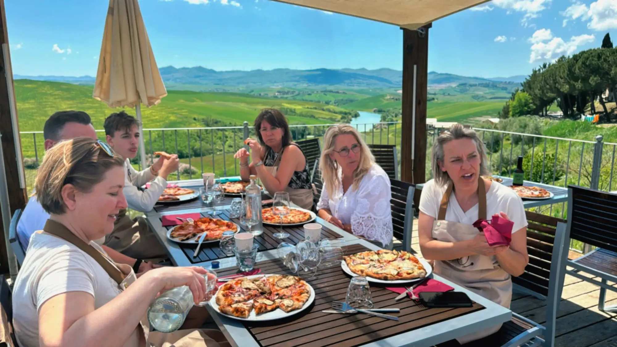 Group enjoying their freshly baked pizzas at a panoramic terrace over the Tuscan hills