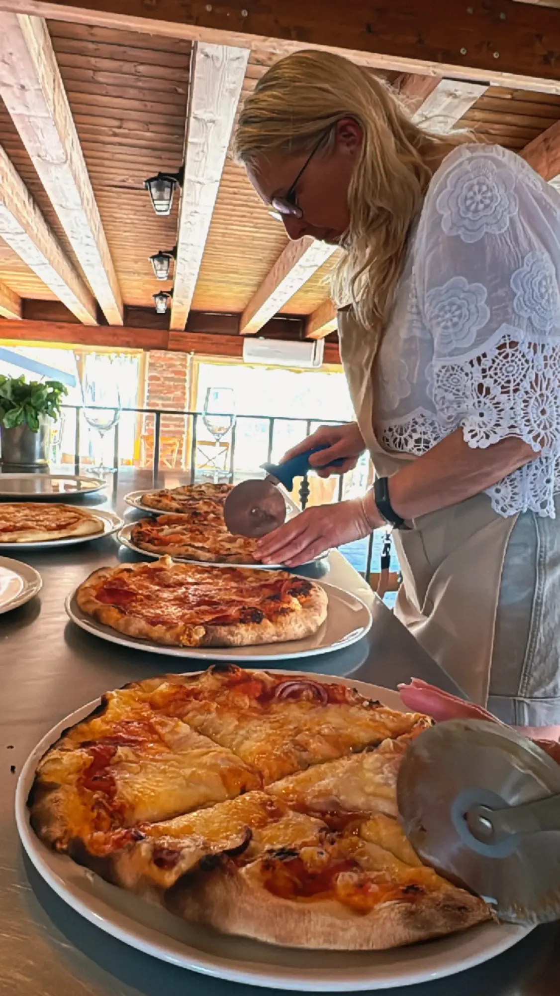 Host slicing freshly baked wood-fired pizzas on the table